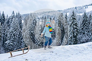 Boy enjoy a sleigh ride. Child sledding, riding a sledge. Children play in snow in winter. Outdoor kids fun for