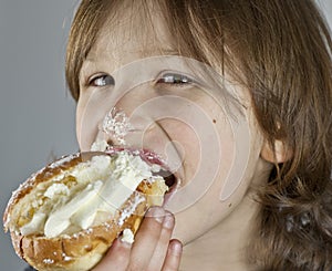 Boy enjoying a cream bun with almond paste