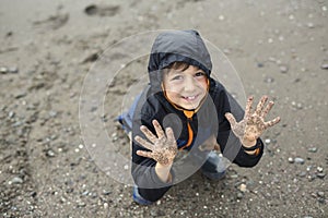 Boy enjoying the rain and having fun outside on the beach a gray rainy