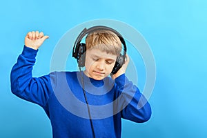 The boy enjoys listening to music through headphones and twitches while holding the headphones with one hand and waves around with