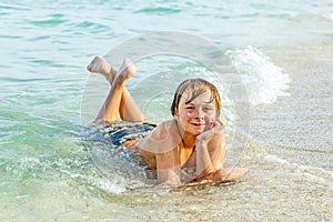 Boy enjoys lying at the beach in the surf