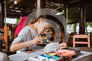 Boy enthusiastically paints clay handicrafts with paint