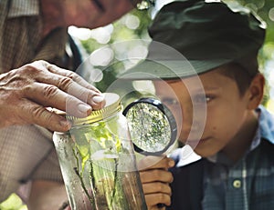 Boy examining a plant with a magnifying glass