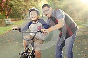 Boy exercises to ride a bike with his dad