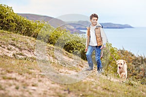 Boy Exercising Dog On Leash Walking Up Hill By Sea