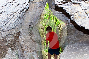 The boy exits the cave in the rock, the rear view. photo