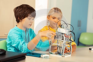 Boy explaining his classmate principals of working of his project.