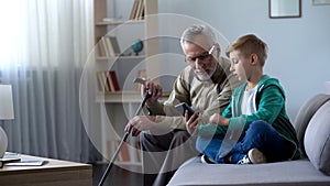 Boy explaining to grandpa how to use cell phone, simple technologies for old man