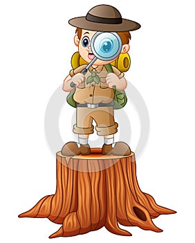 Boy explorer with magnifying glass on tree stump