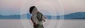 Boy exploring, looking through a telescope standing by the sea