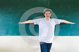 Boy extend the arms with book on head, standing before chalkboard, punishing