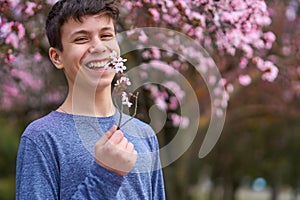 Boy with a face mask is in the city outdoor, blooming trees, spring season, flowering time - concept of allergies and health