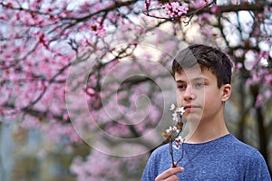 Boy with a face mask is in the city outdoor, blooming trees, spring season, flowering time - concept of allergies and health