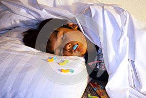 A boy fall asleep while secretly eating candy in bed. Sleep without  brush the teeth routine. Unhealthy lifestyle poor oral hygien photo