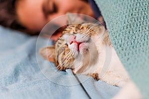 boy falls asleep and hugs his cat, who sleeps with him under the covers. children and pets. the cat sleeps with the baby