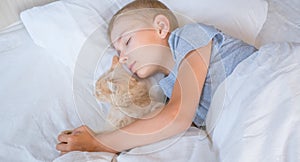 the boy falls asleep and hugs his ginger cat, who sleeps with him under the covers. children and pets. the cat sleeps