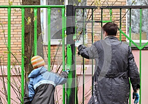 Boy and father, they dye fence by green color