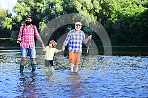 Boy with father and grandfather fly fishing outdoor over river background. Man in different ages. Hobby and sport