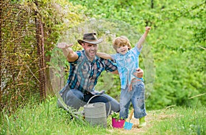 Boy and father in nature with watering can. Spring garden. Dad teaching little son care plants. Personal example. Little