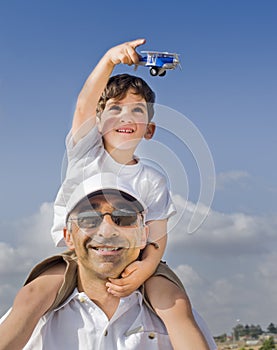 Boy on father shoulders with toy airplane