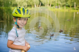 Boy feeding ducks and pigeons in the park by the lake