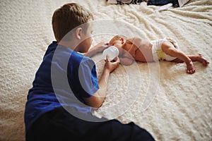 Boy feeding newborn baby with bottle of milk