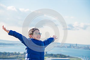 Boy feeling fresh,open arm on the hill