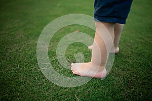 Boy feet in nature. bare feet in the green grass. little Happy child running at sunset barefoot outdoor.