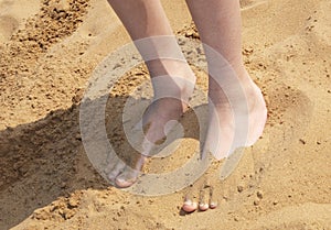 Boy with feet partly buried in sand