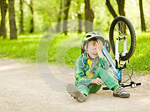 Boy fell from the bike in a park photo