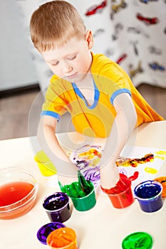 Boy finger paints on paper