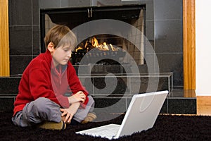 Boy at Fireplace on Computer.