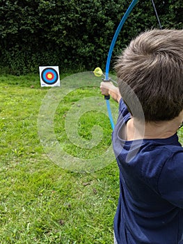 Boy fires arrow dart at a target with his bow