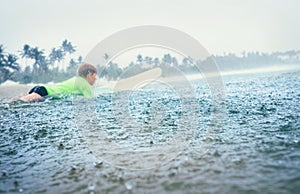 Boy first step surfer learning to surf under tropical rain