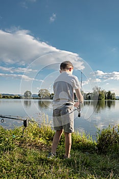 Boy fishing on a lake. Beautiful fish pond near Badin, Banska Bystrica, Slovakia. Fishing place. Shining sun over the fish pond in