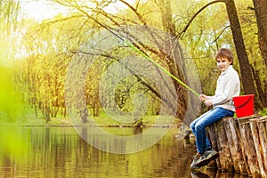 Boy fishing near the pond with green fishrod