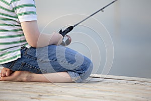 Boy fishing off dock in summer