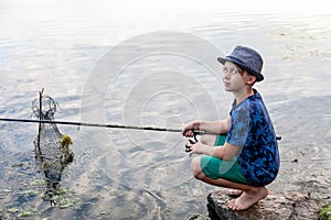 Boy with a fishing rod catches a fish