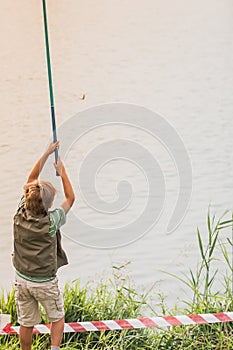 A boy with a fishing rod fishes on the lake,a river,a sea