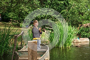 Boy with fishing rod fishing in a wooden boat