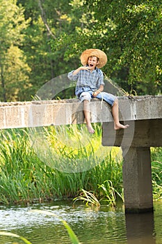 Boy fishing with rod at straw hat