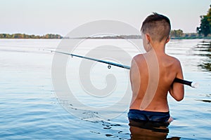 Boy fishing waist deep in water photo