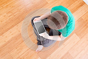 Boy on the Floor Holding Tablet in High Angle View