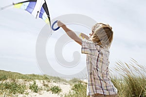 Boy Flying Kite On A Windy Beach