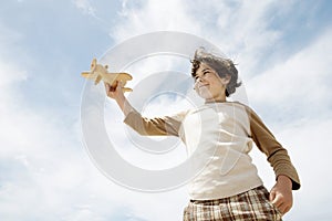 Boy Flying Toy Airplane Against Cloudy Sky