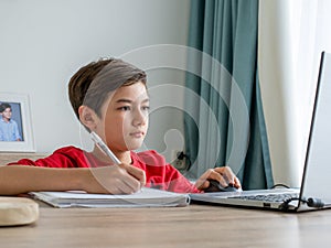 A boy focusing on study, writing on paper. homeschooling concept