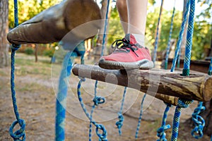 Boy foot shoe close up in adventure climbing high wire park - people on course in mountain helmet and safety equipment