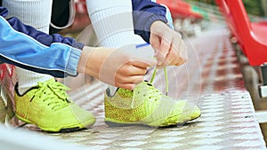 Chico fútbol americano vinculante cordones sobre el zapatos sobre el herboso fútbol americano estadio 