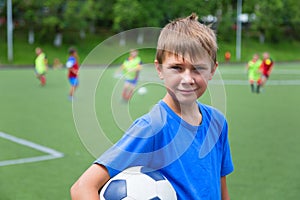 Boy footballer with a ball on soccer field