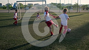 Boy footballer is dribbling ball and kicking goal